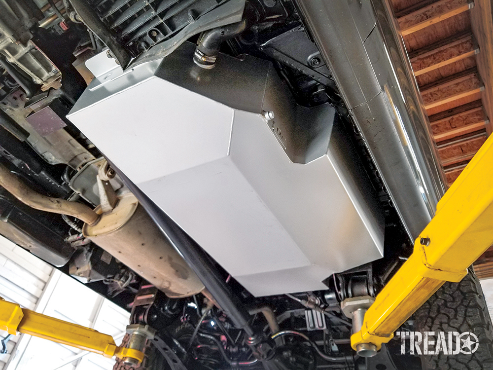 The Mitsubishi Delica Space Gear's silver LRA replacement tank is installed and photographed while on vehicle lift with yellow arms.