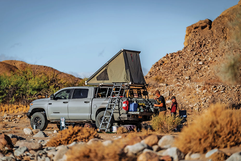 The Tundra, parked at the base of a rocky hill, with the roof top tent and ladded deployed.