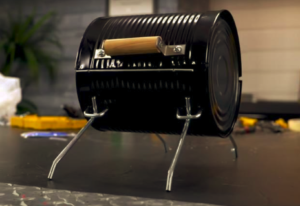 A tin can that has been remodeled to look like a tiny barbecue.