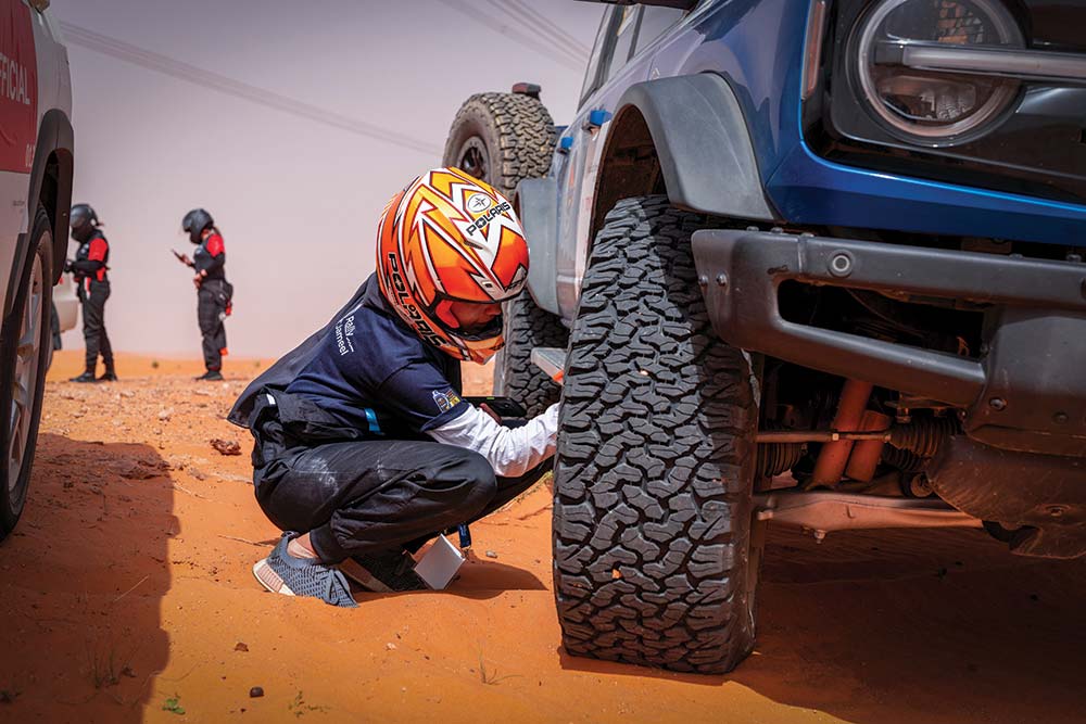 Driver kneels down by a car at the Rally