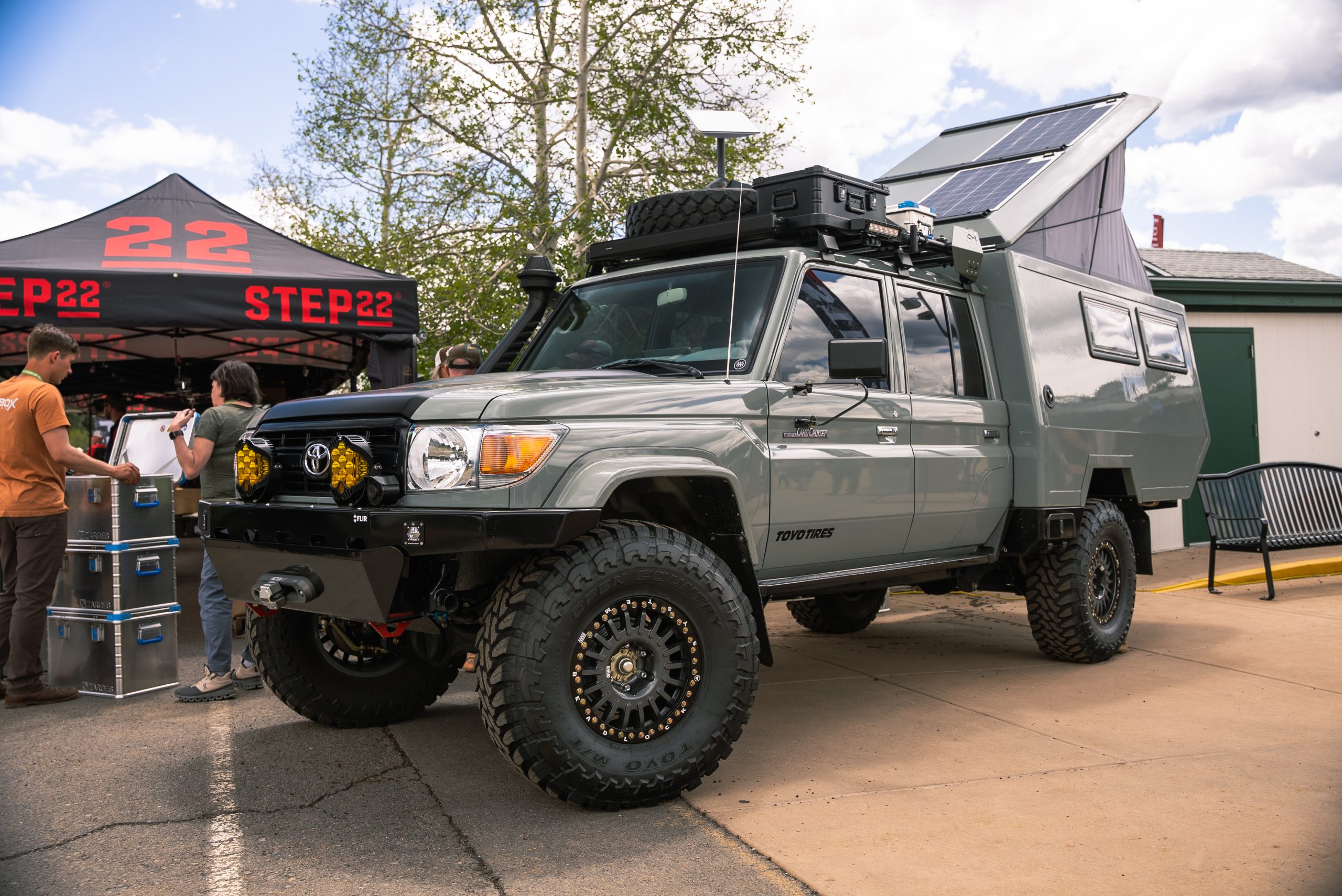 A gray/green Land Cruiser with camper slide-in at the Step22 tent at Overland Expo West.
